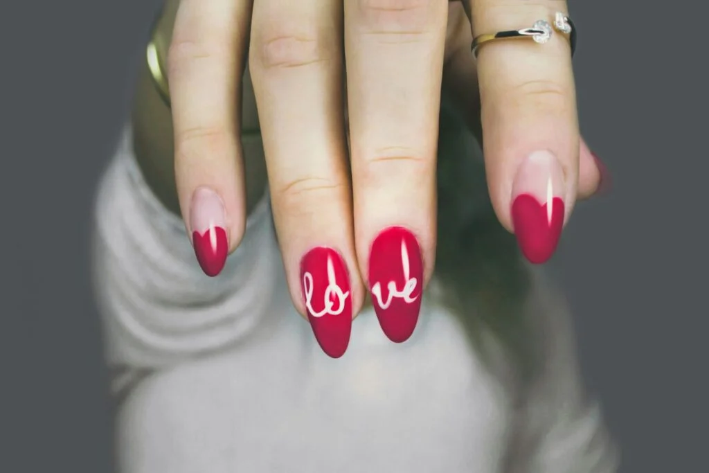 Guide pratique pour retirer le vernis permanent 1 Une main de femme avec une manucure rouge et blanche